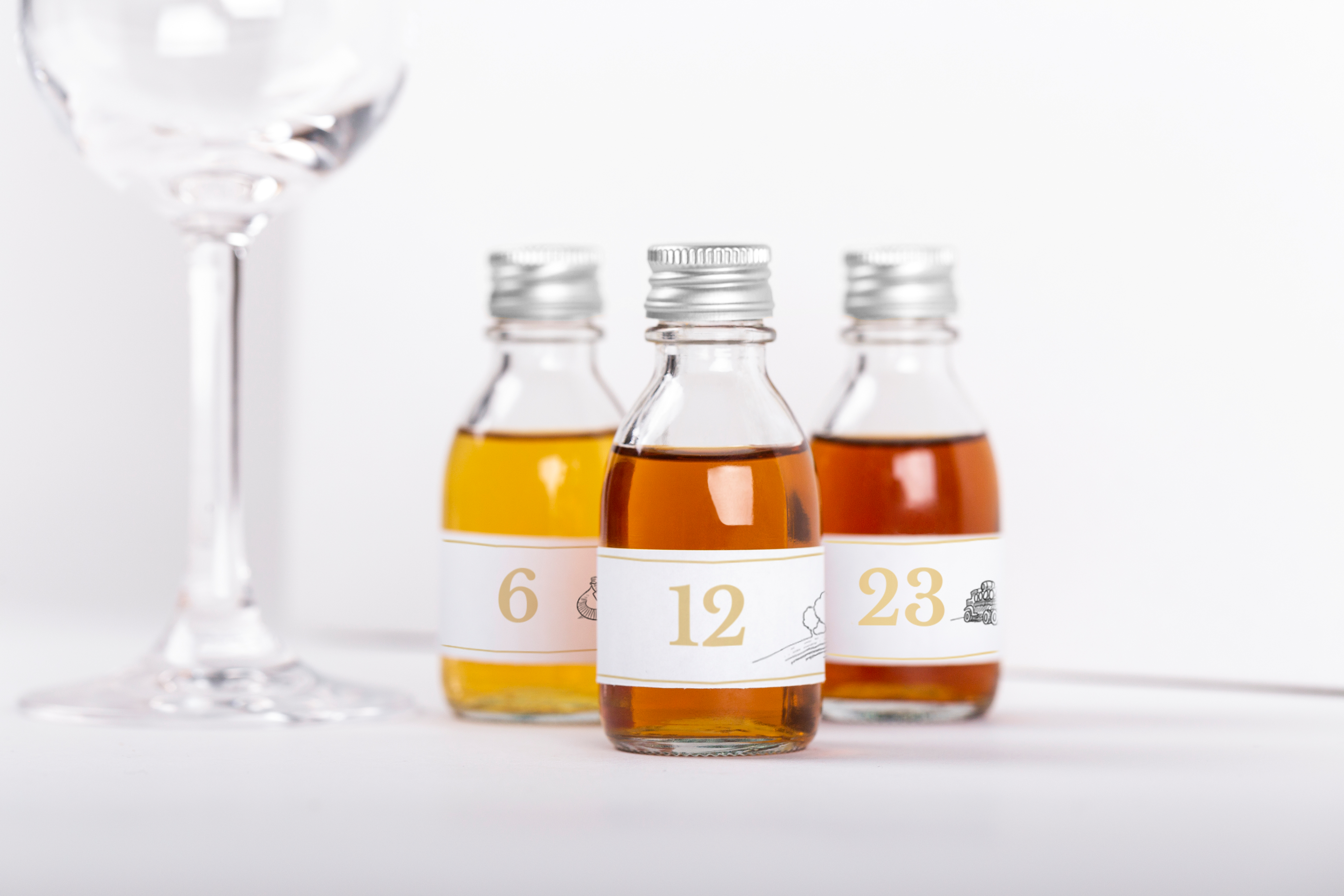 3 cognac sample bottles next to tasting glass